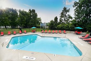 A swimming pool with red lounge chairs and umbrellas